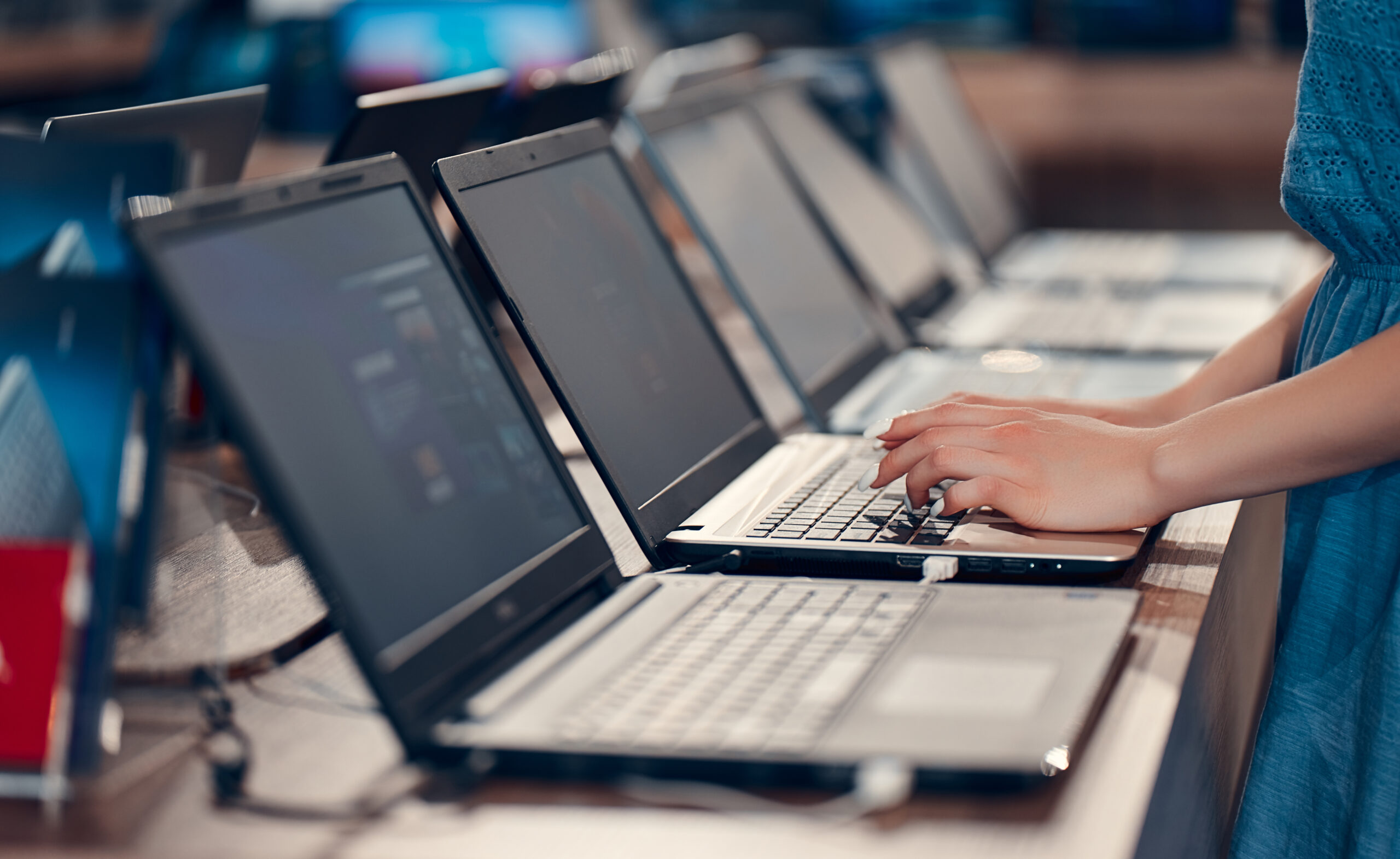 A young girl is testing a laptop in an electronics store. Buying