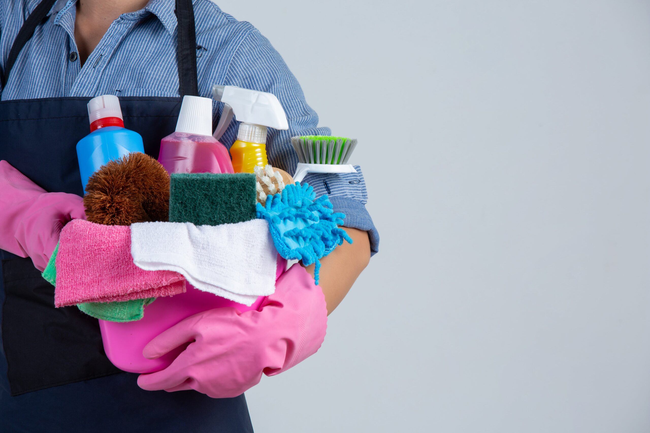 woman-is-holding-cleaning-product-gloves-rags-basin-white-wall-2-min